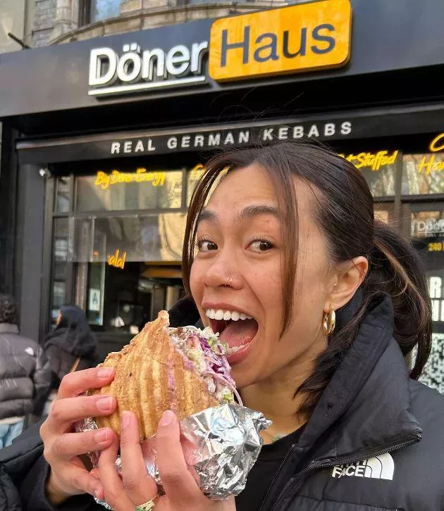 A customer eating a stuffed pide döner standing outside the shop