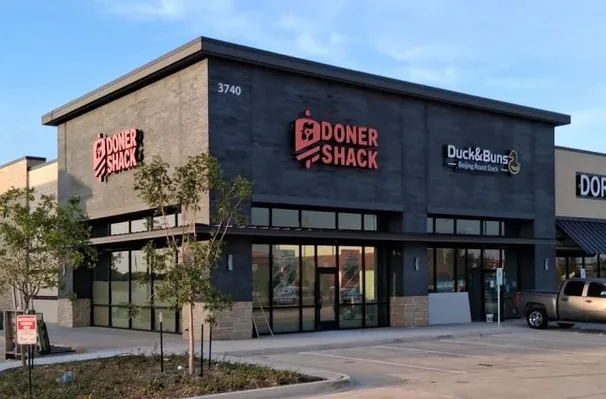 A signed Doner Shack storefront in Prosper, Texas, with a dark interior and boarding against the glass