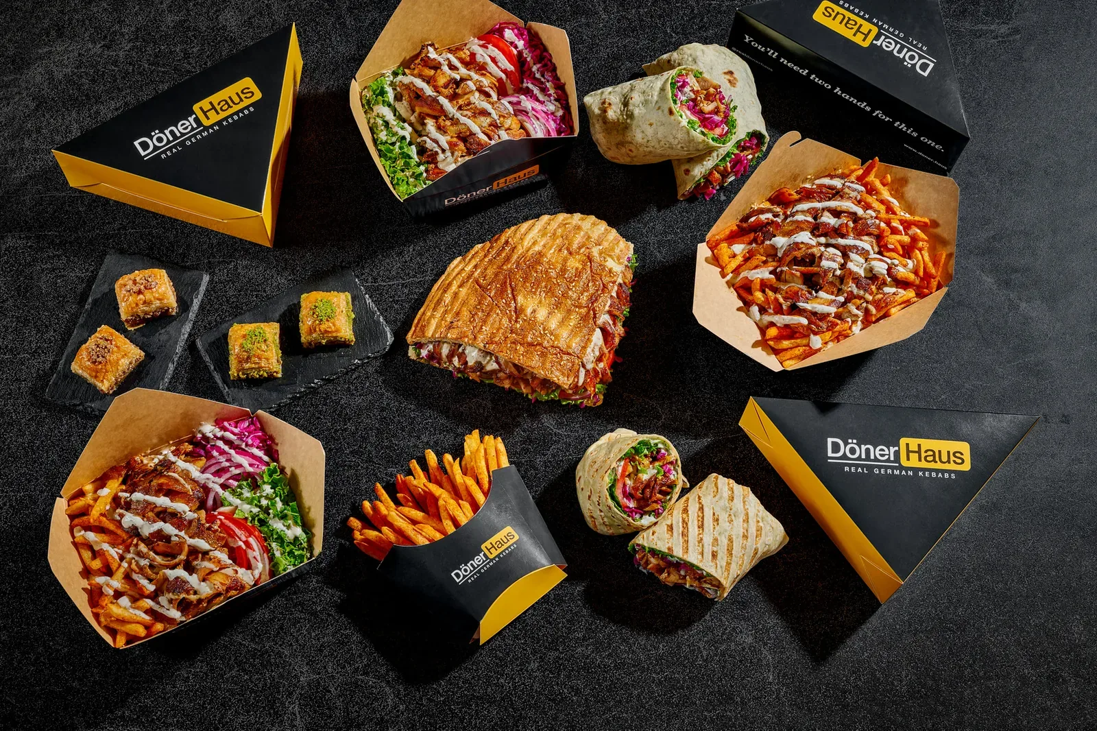 Sandwiches, wraps, döner boxes and fries laid out on slate